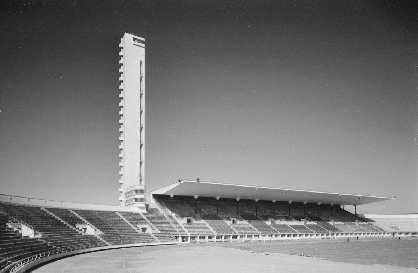 Mustavalkokuvassa Olympiastadionin katettu pääkatsomo, kenttää ja torni. Kaikki on tyhjää, eikä kuvassa ole ihmisiä.. Kuvaaja: Viljo Pietinen, Historian kuvakokoelma / Museovirasto. Mustavalkokuvassa Olympiastadionin katettu pääkatsomo, kenttää ja torni. Kaikki on tyhjää, eikä kuvassa ole ihmisiä.. Kuvaaja: Viljo Pietinen, Historian kuvakokoelma / Museovirasto.