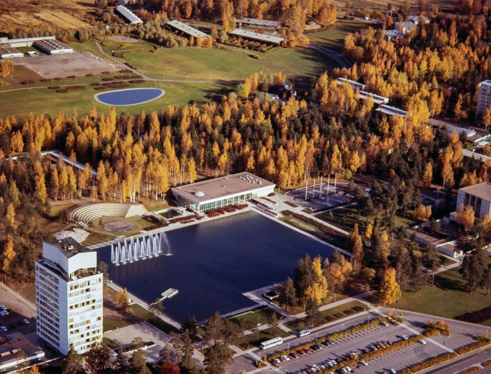 Ilmakuvassa Tapiolan keskusallas ja rakennuksia ruskaväristen puiden ympäröimänä. Ilmakuvassa Tapiolan keskusallas ja rakennuksia ruskaväristen puiden ympäröimänä.