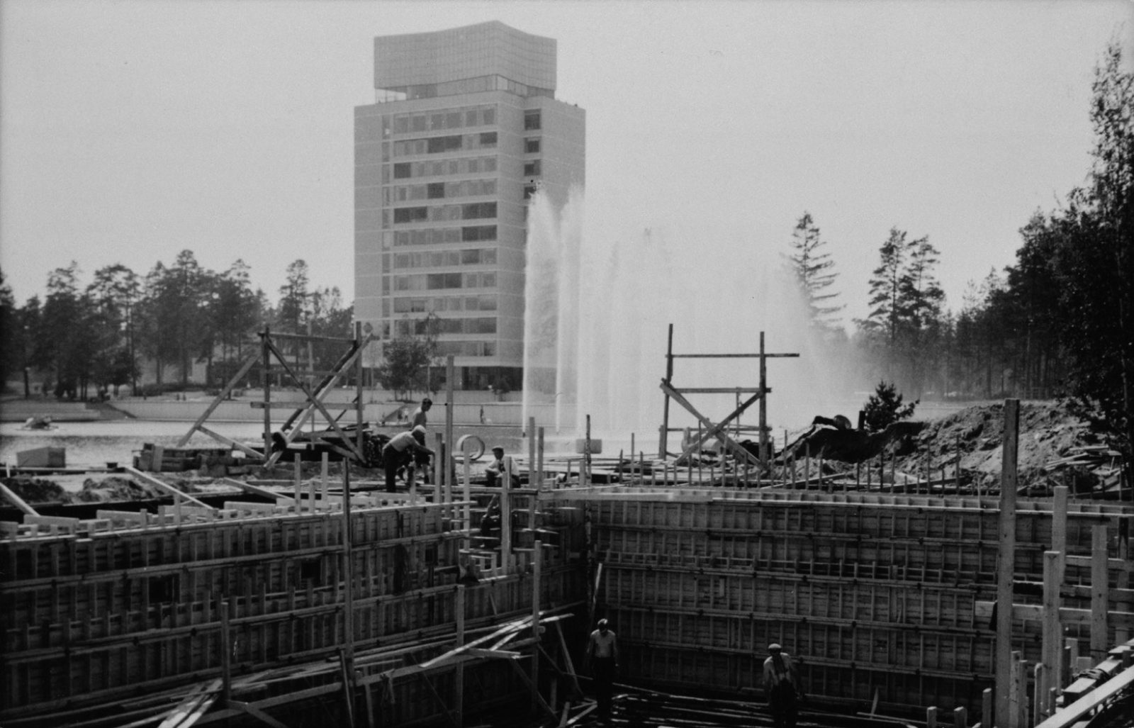 Mustavalkokuvassa betonia valetaan puukehikkojen avulla. Taustalla Tapiolan keskustorni. Mustavalkokuvassa betonia valetaan puukehikkojen avulla. Taustalla Tapiolan keskustorni.