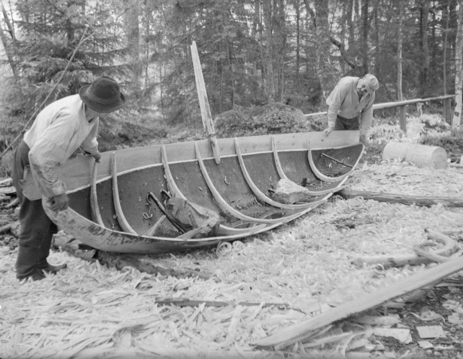 En extra bräda läggs på en stockbåt i asp i Vittisbofjärd, 1935. Foto: Eino Nikkilä / Museiverkets Bildsamlingar. Objektinumero: KK1976:97 En extra bräda läggs på en stockbåt i asp i Vittisbofjärd, 1935. Foto: Eino Nikkilä / Museiverkets Bildsamlingar. Objektinumero: KK1976:97