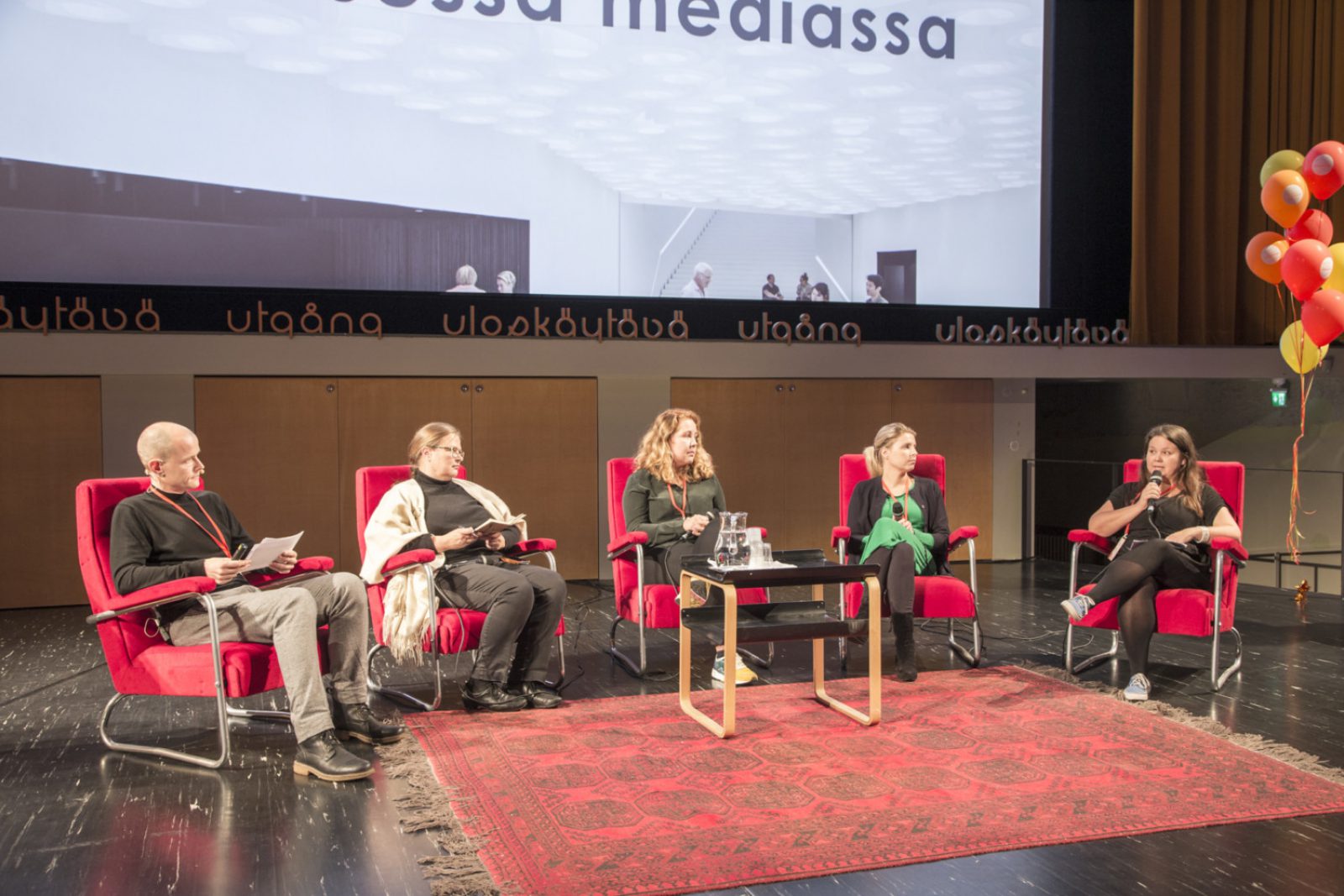 Viisi ihmistä nojatuoleissa esiintymislavalla.. Kuvaaja: Soile Tirilä