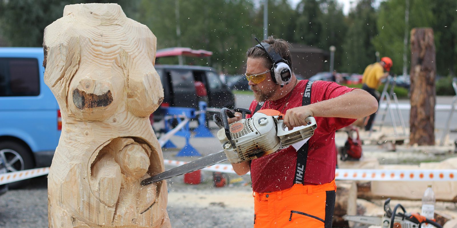 Mies veistää puuta moottorisahalla. Puusta hahmottuu raskaana oleva nainen.. Kuvaaja: Eero Knaapi. Maaseudun Sivistysliiton kuva-arkisto. Mies veistää puuta moottorisahalla. Puusta hahmottuu raskaana oleva nainen.. Kuvaaja: Eero Knaapi. Maaseudun Sivistysliiton kuva-arkisto.