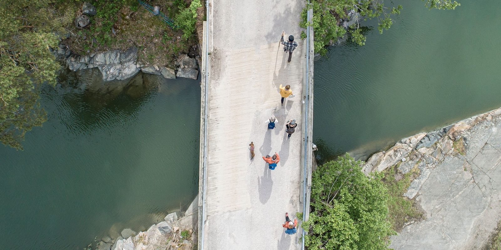 Kapean joen ylittävä silta kuvattuna suoraan yläpuolelta. Sillalla on useita ihmisiä kävelemässä kohti kuvan ylälaitaa.. Kuvaaja: Jouni Lappi