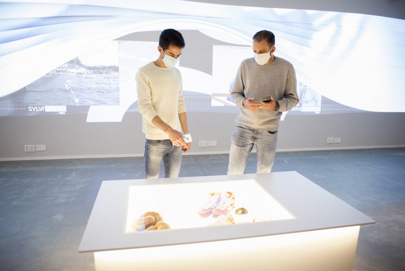 Två museibesökare med ansiktsmasker vid utställningsföremålen. Två museibesökare med ansiktsmasker vid utställningsföremålen.