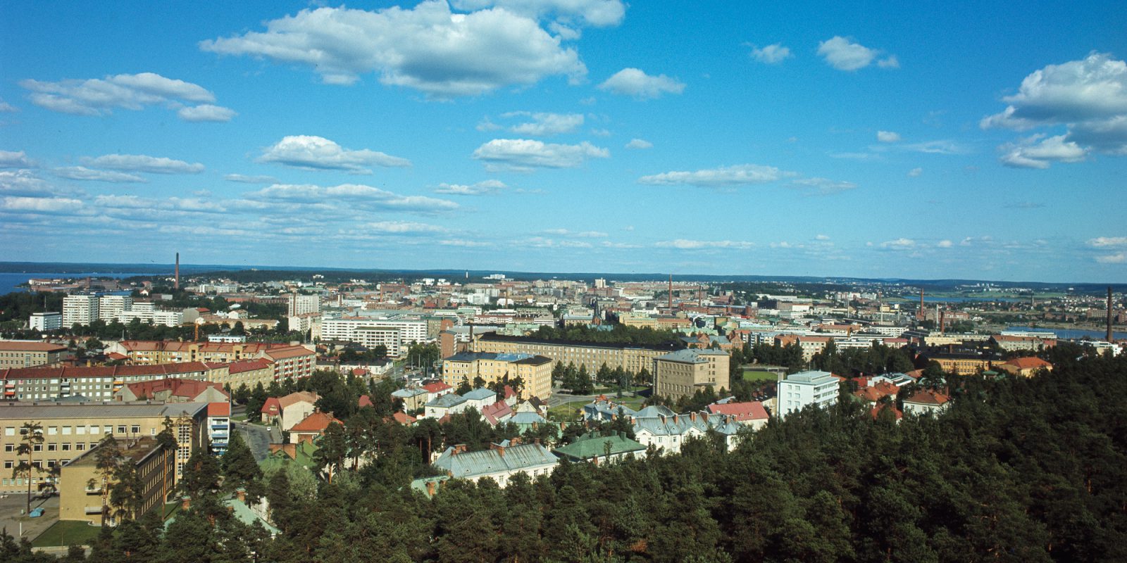 Tampereen kaupunki kuvattuna korkealta. Etualalla kaistale havupuita. Taivaalla yksittäisiä pilviä.. Kuvaaja: Teuvo Kanerva. Kohdenumero:HK19940104:2558 Tampereen kaupunki kuvattuna korkealta. Etualalla kaistale havupuita. Taivaalla yksittäisiä pilviä.. Kuvaaja: Teuvo Kanerva. Kohdenumero:HK19940104:2558
